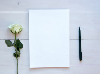 Romantic mood mock up for your text and design, top view, flat lay, notepad with white rose at rustic wooden background. Blank greeting card or illustration sheet, copy past.