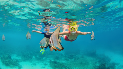 Happy family - mother, kid in snorkeling mask dive underwater, explore tropical fishes Platax ( Batfish). Travel lifestyle, beach adventure, swimming activity on summer with child. Focus on fishes - obrazy, fototapety, plakaty
