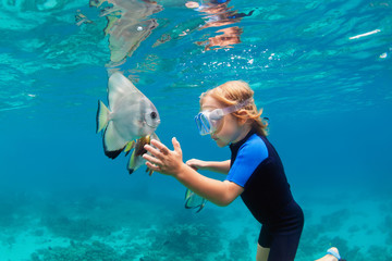Happy family - active kid in snorkeling mask dive underwater, see tropical fish Platax ( Batfish )...