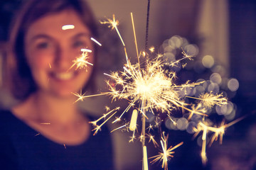 Happy girl is holding a sparkler at Christmas time