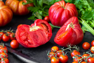 Red, ripe tomatoes and celery on a dark background. Harvesting tomatoes. Top view.