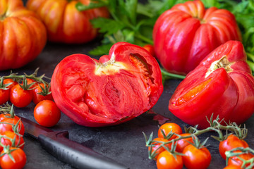 Red, ripe tomatoes and celery on a dark background. Harvesting tomatoes. Top view.