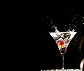 Cocktail with strawberries isolated on black background.Glass of vodka splashing.