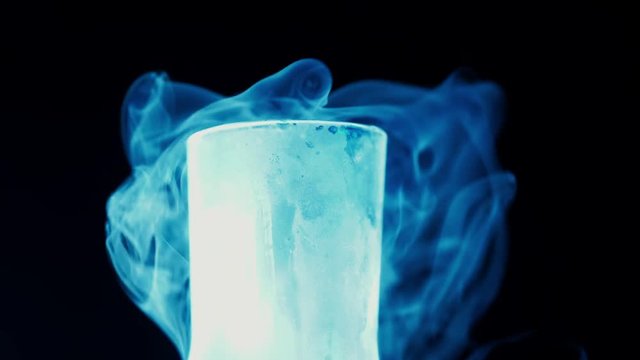 Flask with liquid nitrogen on black background. Concept of chemical experiments and tests. Edutainment. 4k