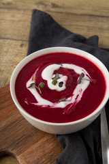 plate with beetroot soup and sour cream on wooden background, top view