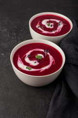 two plates with beetroot soup and sour cream on black background