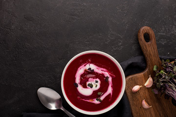 two plates with beetroot soup and sour cream on black background