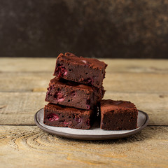 Brownie dessert slices with cherry on a plate, wooden background