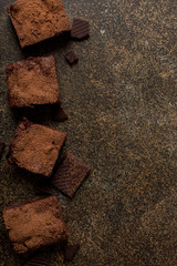 Brownie dessert slices on brown background with chocolate, top view