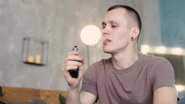 Handsome young man smoking electric