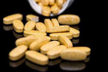 Orange pills close up macro shot on shiny black surface.