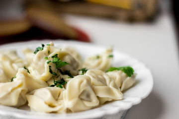 Traditional russian pelmeni, ravioli, dumplings with meat on dark concrete background. Parsley, pepper, and spices.