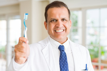 Middle age dentist man holding toothbrush and smiling