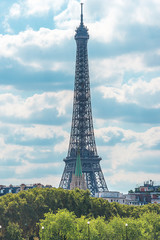 Beautiful view of Eiffel Tower against the white clouds on the blue sky on sunny summer day. Vertical picture