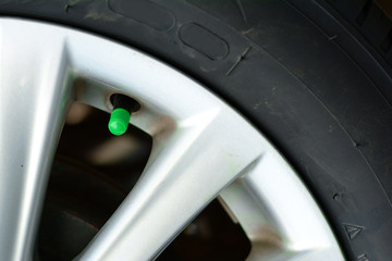the green cover of tyre pressure valve on metal wheel with   black tyre