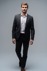 Perfect suit. Full length of handsome young man in suit looking at camera while standing against gray background