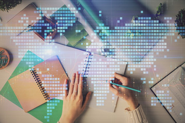 Double exposure of World map polygonal with person writing in notepad. Globalization concept.