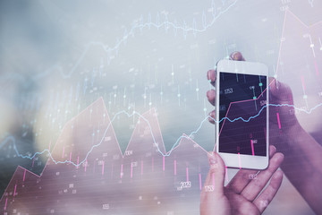 Double exposure of businessman using cell phone and stock market charts. Financial concept.