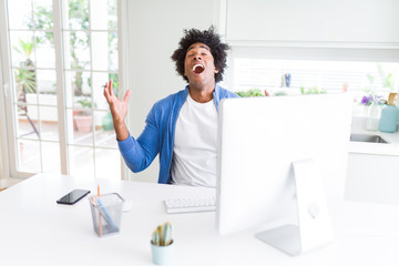 African American man working using computer celebrating mad and crazy for success with arms raised and closed eyes screaming excited. Winner concept