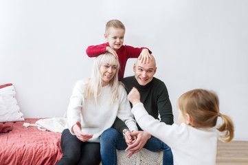 Family of four having fun on the bed at home. Concept of family happiness