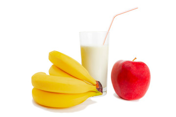 Milk in a glass, bananas and an apple lie next to everything on a white background.