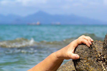 woman's hand out of the water trying to grab the coastal stone and escape from the sea. Close-up. Copy space