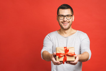 Happy holiday, my congredulations! Portrait of an attractive casual man giving present box and...