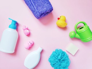 Flat lay composition photography liquid soap, purple towel, baby shampoo, blue sponge and rubber toys. Cosmetics and bath products for kids