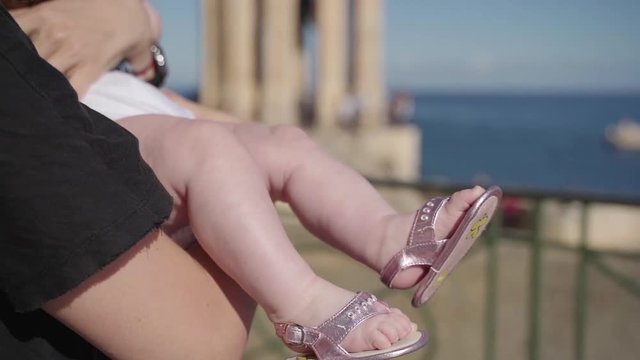 A hot day near the beach on Malta, Valetta; close-up plan of a child's feet in pink sandals