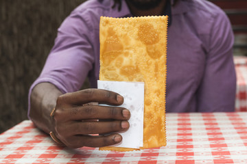 African american man showing brazilian snack known as Pastel - asian recipe.