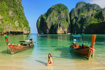 Young woman sitting on the beach at  Maya Bay on Phi Phi Leh Island, Krabi Province, Thailand - obrazy, fototapety, plakaty