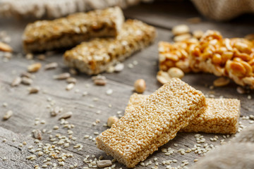 Assorted kozinaki, on old vintage background, with burlap fabric. Country style. Delicious sweets from the seeds of sunflower, sesame and peanuts, covered with shiny glaze.