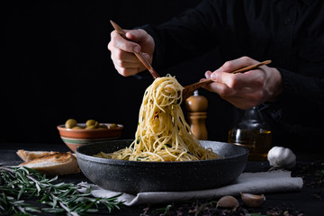Serving traditional  italian pasta from a pan. Male hands taking spaghetti in spoon and fork, shot...