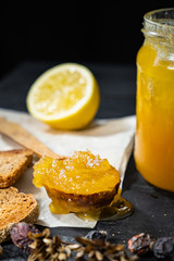 Spoonful of honey on dark rustic background. Crystallized home-made honey in jar, low-key shot
