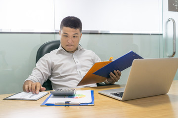 Asian businessman holding document and checking information in notebook