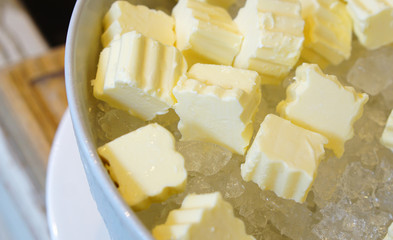 Cubes of fresh butter placing on ice in white bowl. Hotel restaurant breakfast buffet