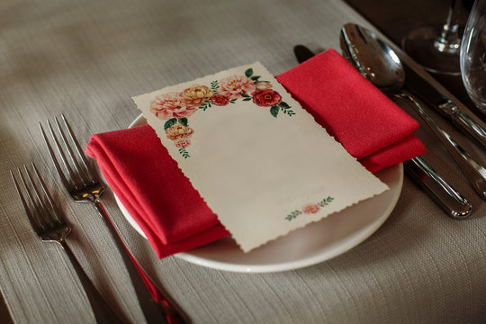 Elegant wedding reception catering, luxury table arrangement - floral greeting card on red napkin near expensive silverware close-up, fine dining concept