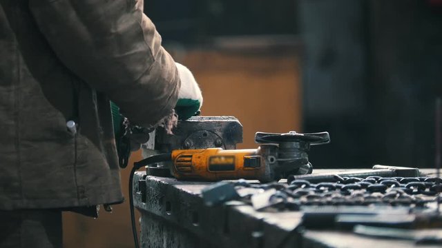 Industrial concept. A man worker measure out a black chain and putting it into the clamp