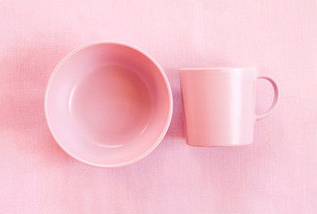 Pink cup and plate on gentle pink cloth background