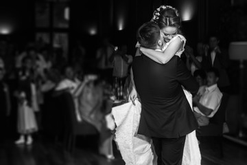 Fototapeta na wymiar wedding couple performing first dance and hugging. luxury bride and groom embracing. tender sensual romantic moment at wedding reception in restaurant. black white photo