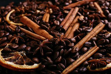 Cinnamon sticks, star anise, coffee beans and dried orange on the kitchen table. Fragrant spices for coffee drink, close-up.