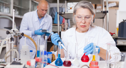 Female biochemists mixing chemicals
