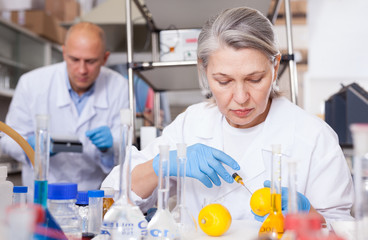 Female lab technician injecting reagent into lemon