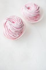 Two pink marshmallow curl on white background. Copy space