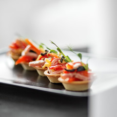 Delicious French snack with ham, cheese, pepper and tomato in tartlets. Concept of food, restaurant, catering, menu.