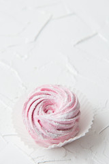 One pink marshmallow curl on white background. Copy space