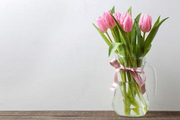 Beautiful bouquet of flowers of pink tulips in a vase against the background of a gray wall. place for text. spring holidays.
