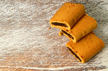 stack of three fig bar cookies on old wooden background or counter.