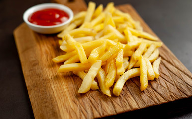 French fries with ketchup on a cutting board, background is concrete