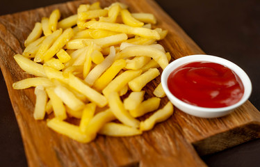 French fries with ketchup on a cutting board, background is concrete